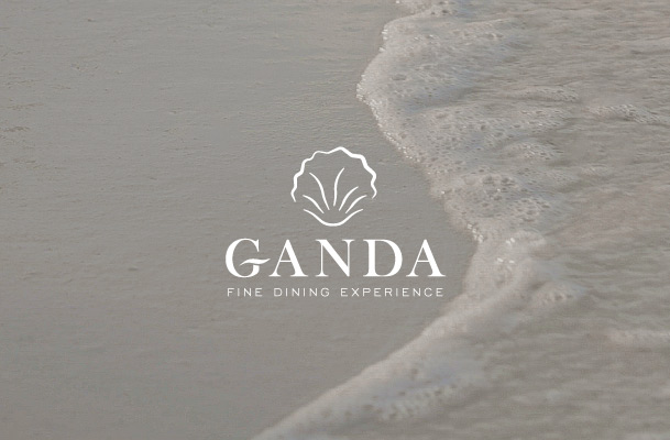 Sea water glides over fine sandy beach and logo of Ganda Fine Dining Experience